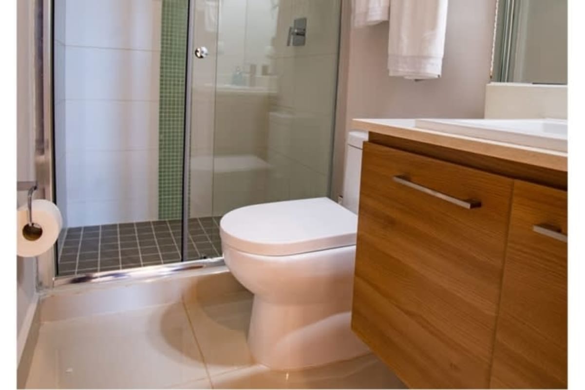Bathroom with glass shower, wood vanity, modern fixtures at PH Alto Río