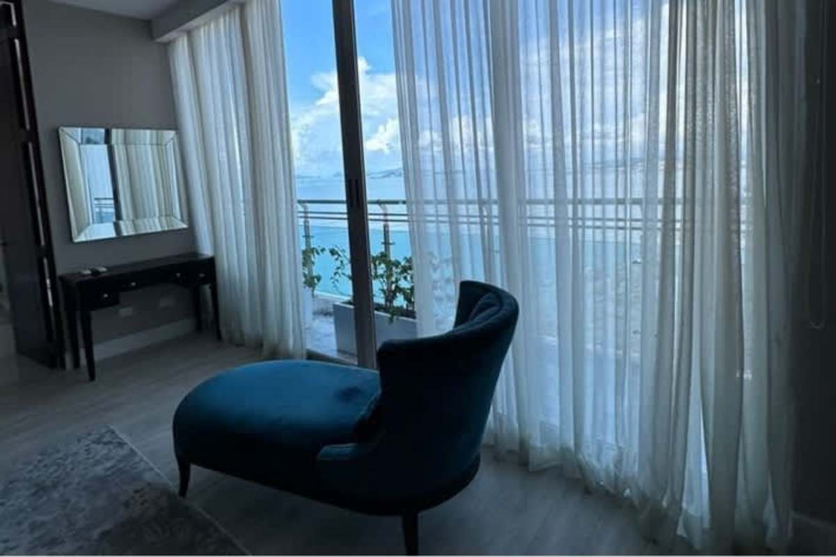 Modern bedroom sitting nook with chaise lounge, balcony access and waterfront view in Punta Pacifica Trump Ocean Club Panama City