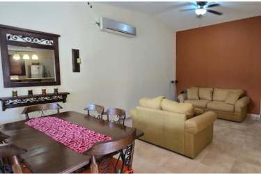 Bright living room featuring beige sofas, accent wall, and decorative mirror in Las Lajas Panama