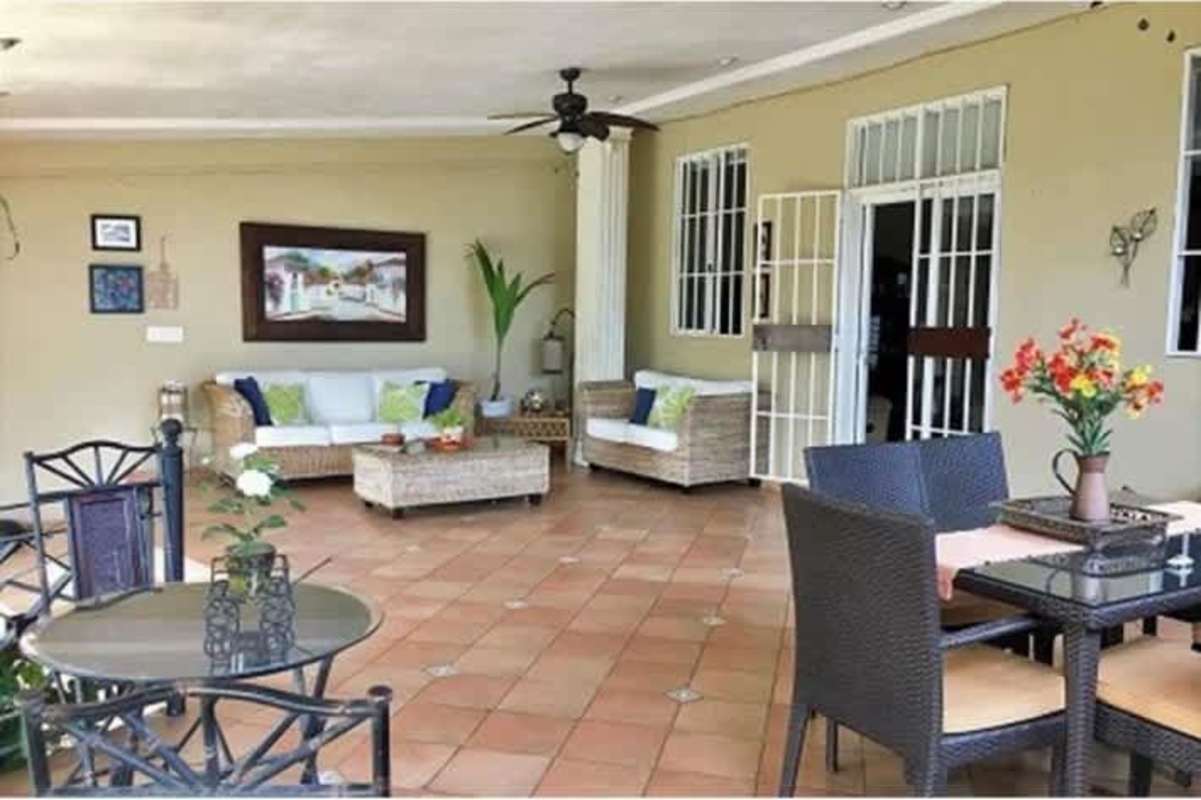 Covered patio with blue cushioned seating, garden views in duplex Betania Panama
