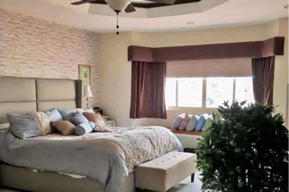 Large bedroom with upholstered headboard, tray ceiling, stone accent wall in duplex Betania Panama