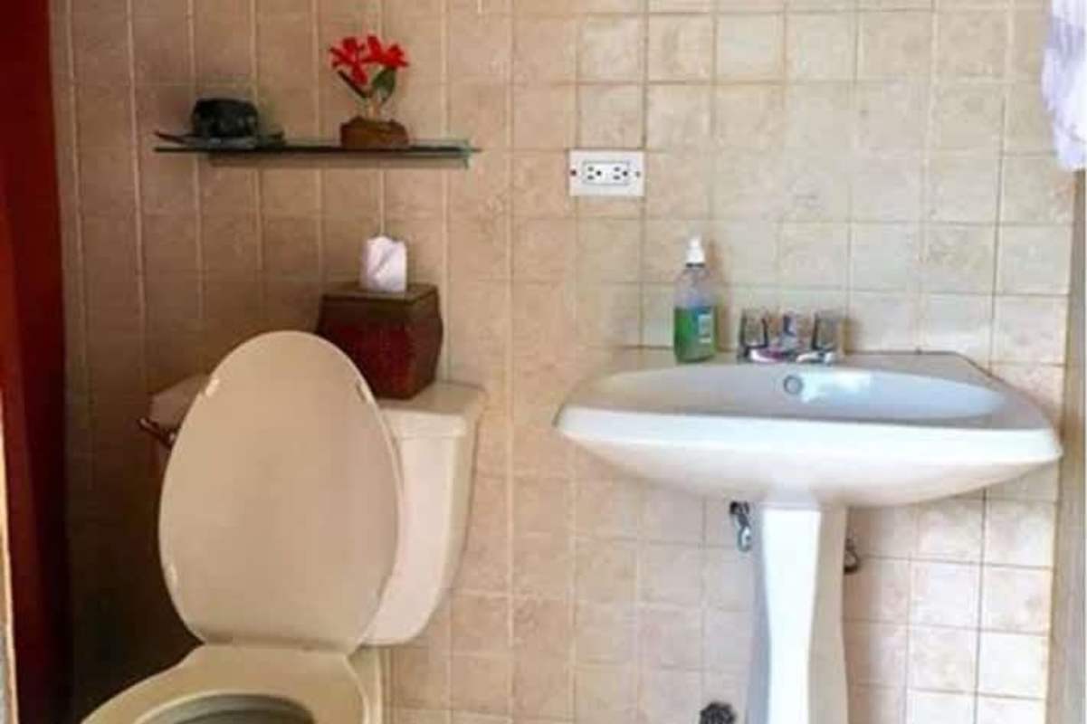 Bathroom with beige tiles, pedestal sink, mirror, in duplex Betania Panama