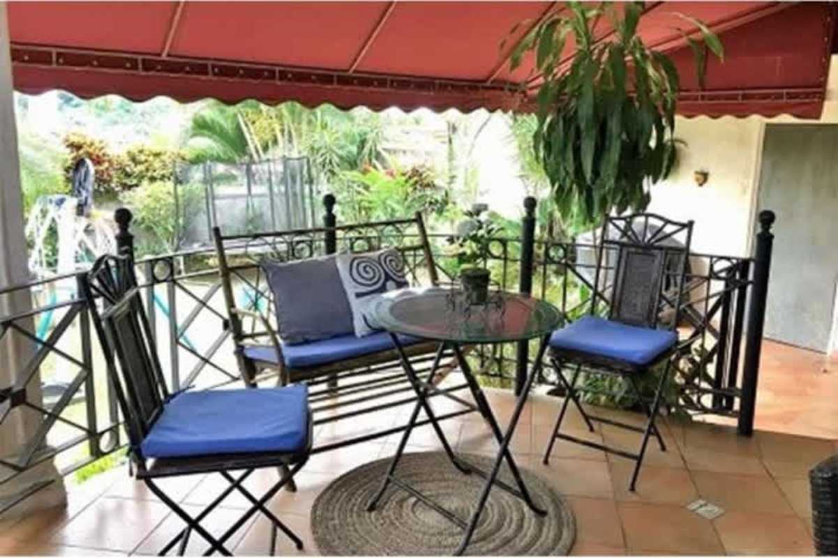 Covered patio with wicker dining furniture, plants, terracotta tiles in Betania duplex