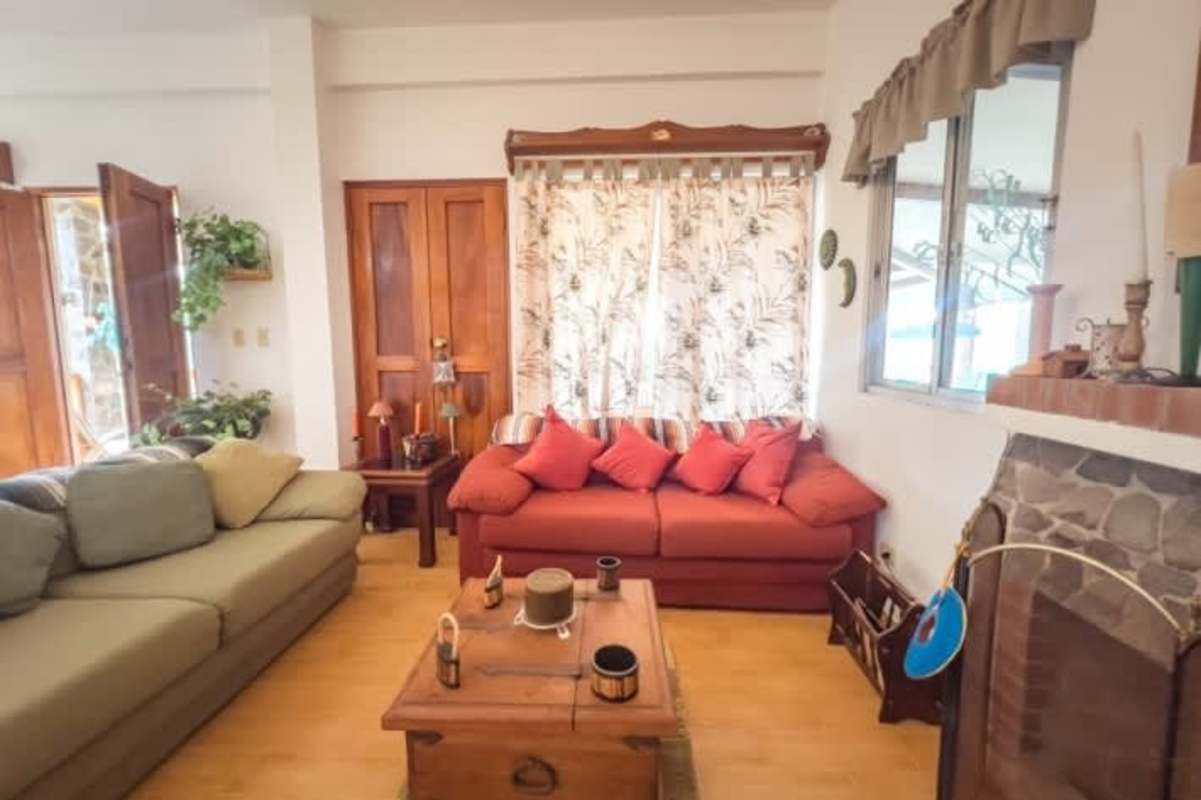 Rustic living room with fireplace, wood floors and garden views in mountain home Panama