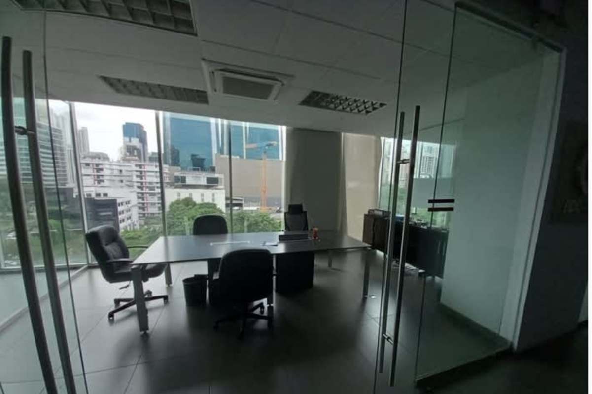 Reception area with glass desk, exposed ducts, and black chairs PH Office One Obarrio Panama