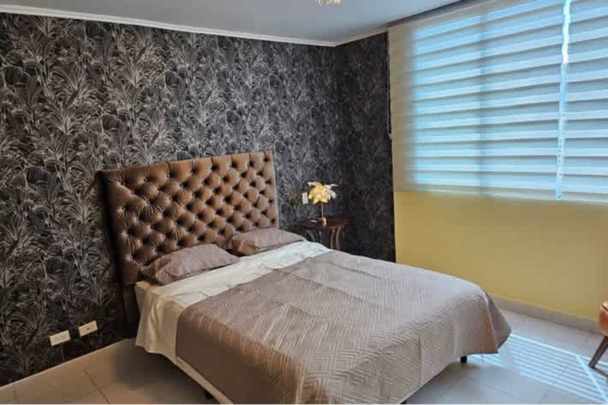 Modern bedroom featuring tufted brown headboard and blinds in PH Miró Panama