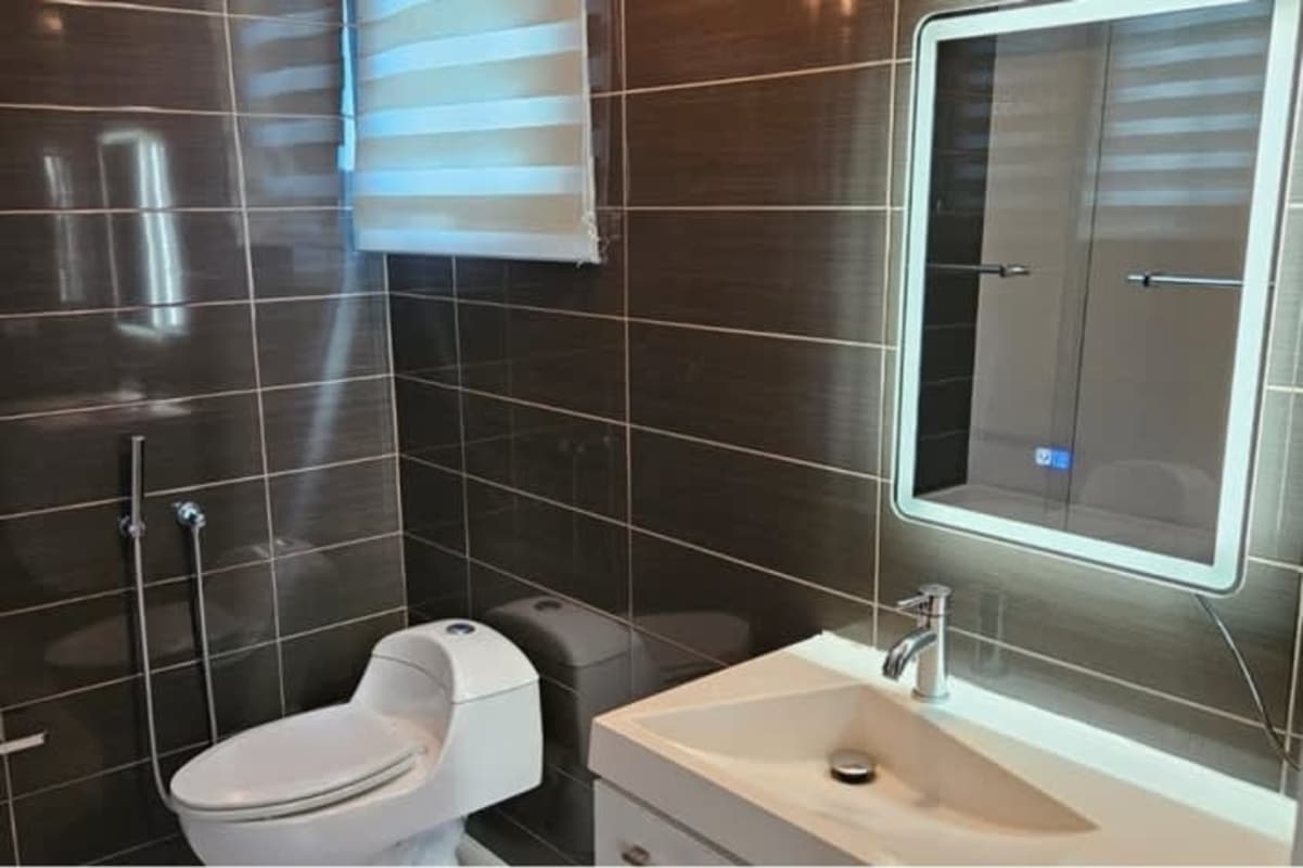 Bathroom featuring dark tiled walls, vanity, illuminated mirror in PH Miró