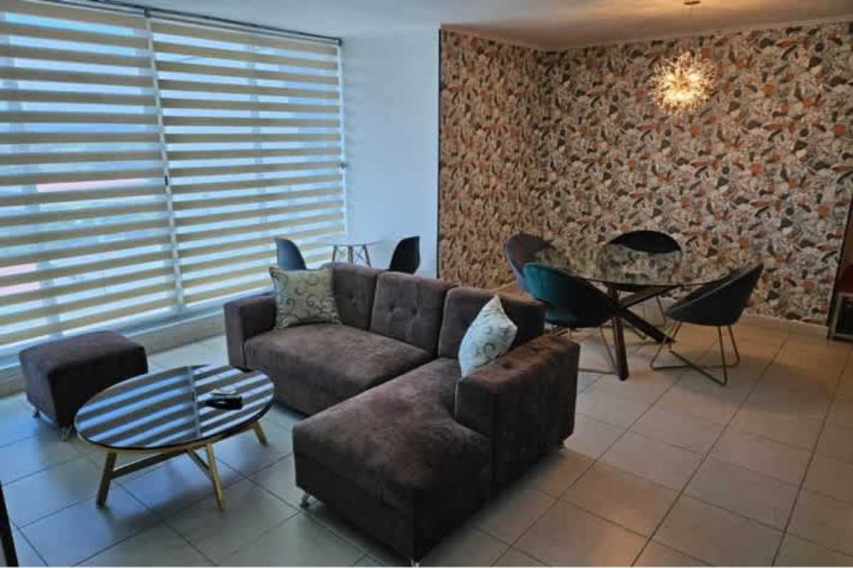 Large windows with striped blinds and sectional sofa at PH Miró apartment Panama