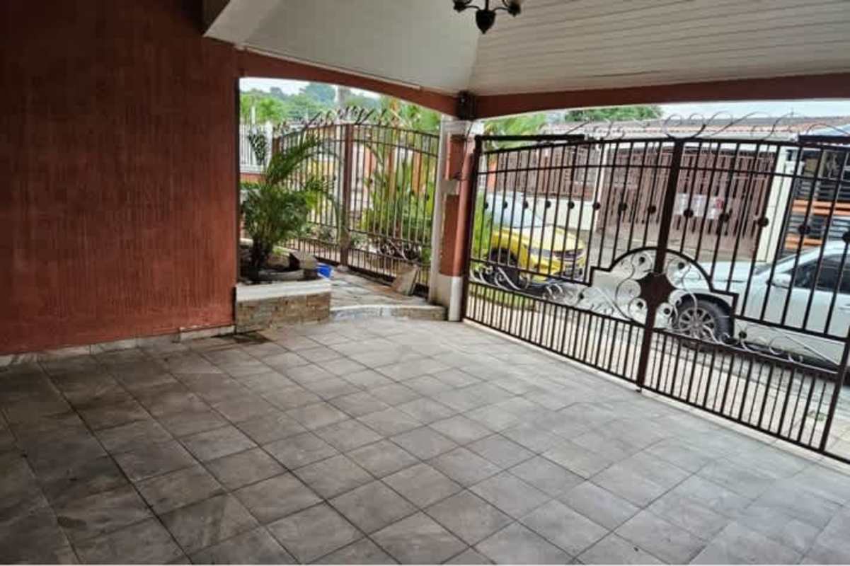 Covered carport area with tiled floor, metal security gate, and potted plants in San Antonio Panama City