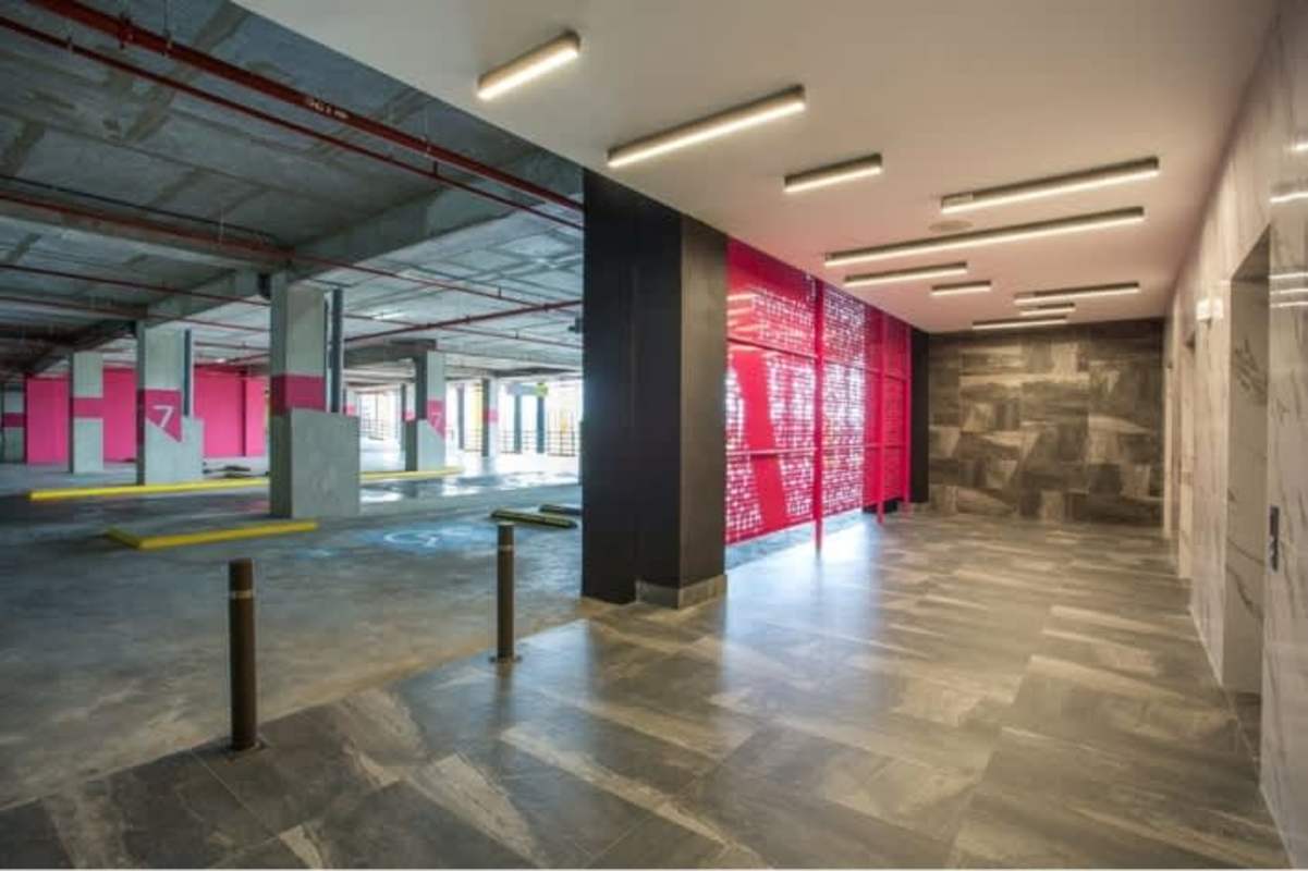Modern parking garage connected to tiled lobby area with red wall at Betania Plaza Panama City