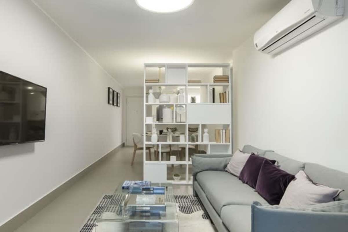 Modern living room with bookshelf, split AC, gray sofa and wall mounted TV in PH Altamira Residences Panama City