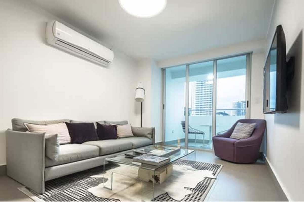 Living space with modern sofa, TV, glass table and balcony doors in PH Altamira Residences Panama City