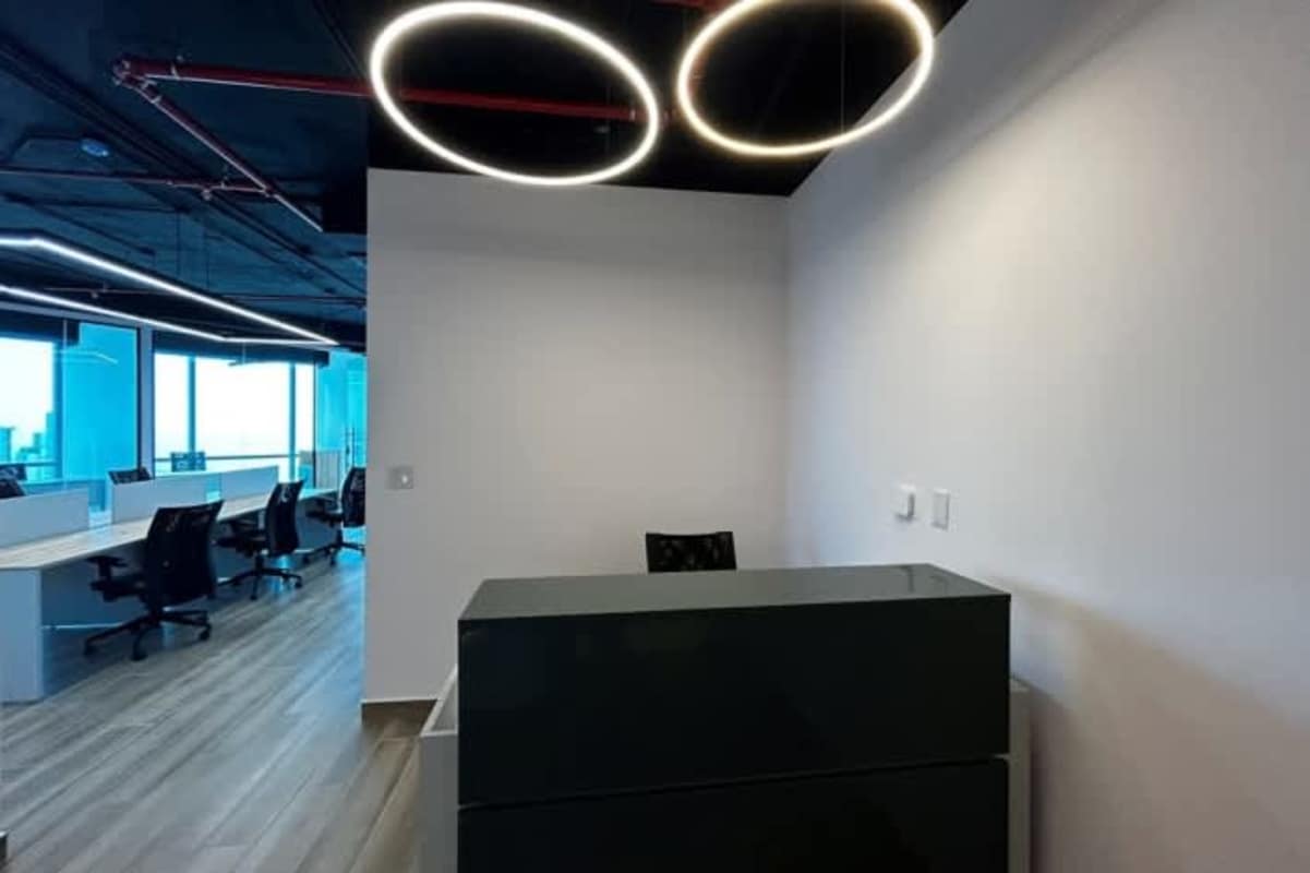 Corporate reception with modern black desk, light fixtures, exposed ceiling Costa del Este