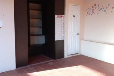 Bright bedroom with tile flooring, bars on window and colorful curtains Panama house for sale