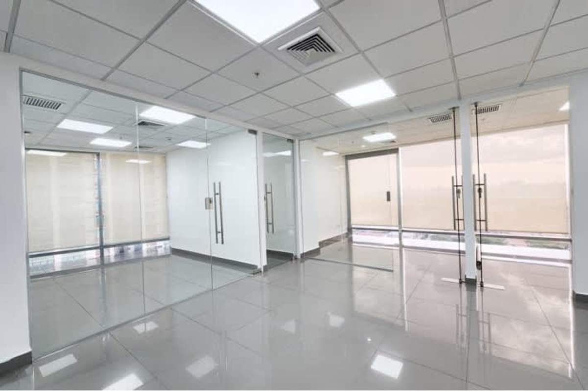 Open plan office with glass walls tiled flooring and ceiling lights at Torre Aseguradora Ancón Costa del Este