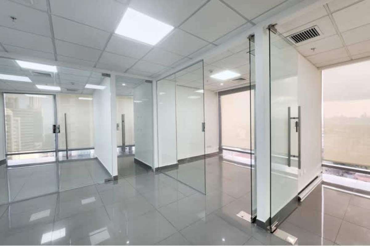 Compact kitchenette with sink wooden cabinets and adjacent bathroom in office tower Costa del Este Panama