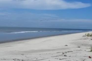 Wide sandy beachfront with ocean waves and clear sky in Punta Chame Panama