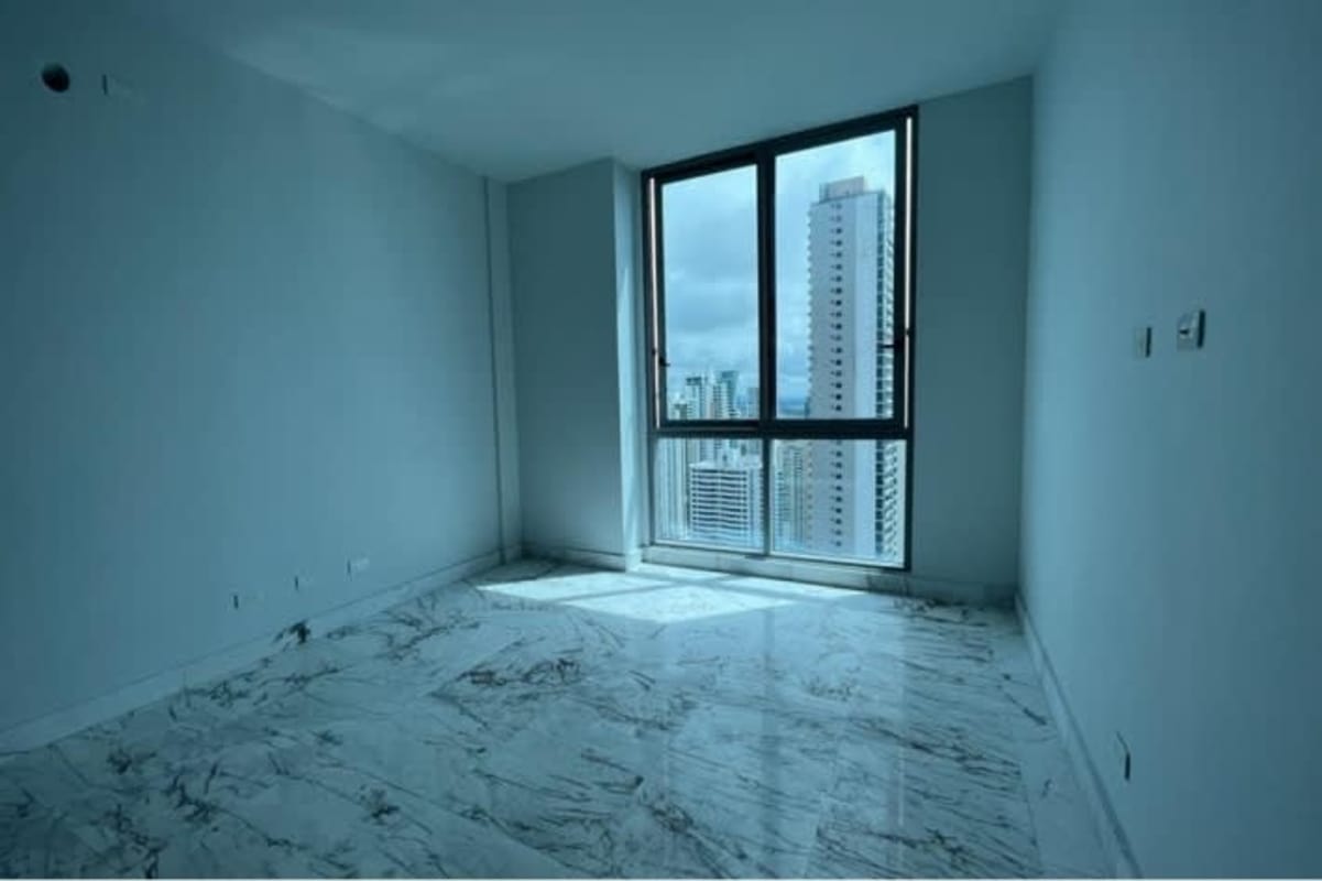 Modern bedroom with marble flooring, full glass vista of city skyline and Pacific Ocean in luxury penthouse