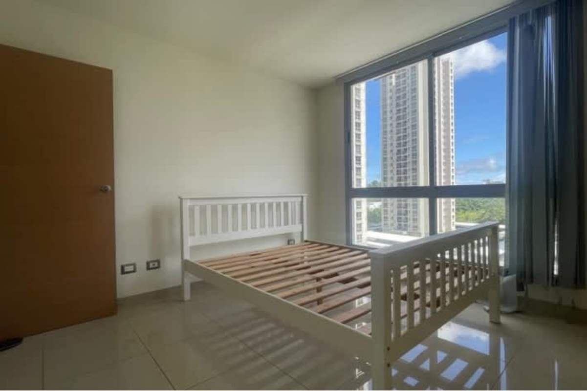 Bright bedroom with built-in closets and large window overlooking Panama skyline