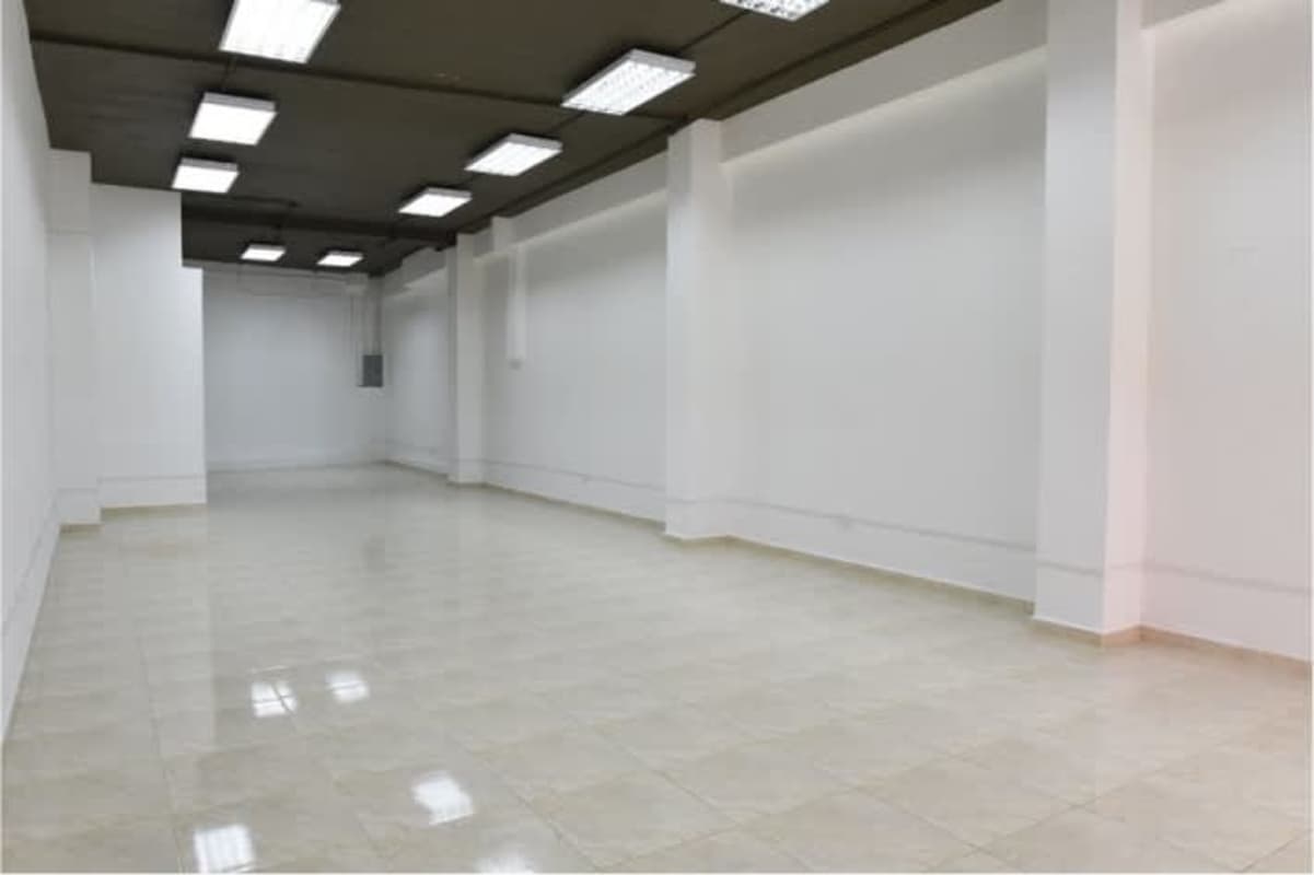 Commercial interior with high ceiling, white walls, fluorescent lights at Avenida Central Panama City