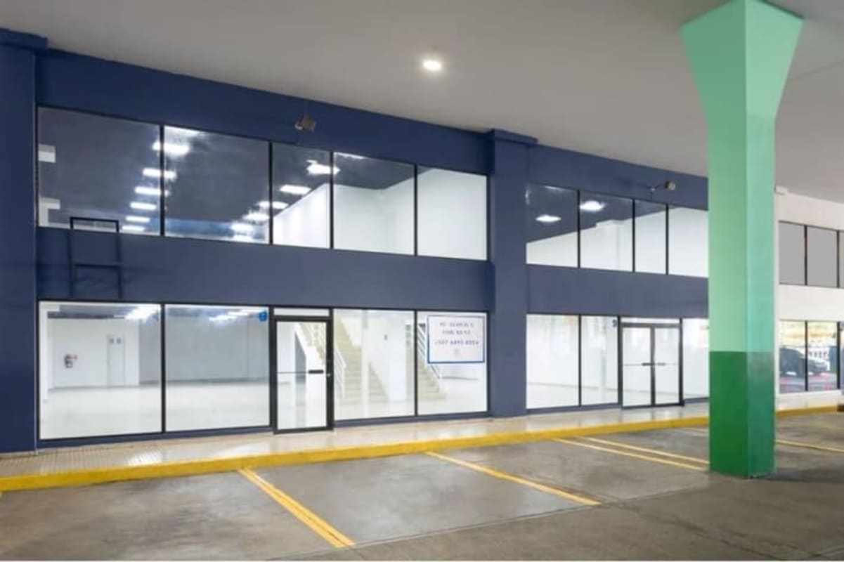 Two-story commercial retail exterior with signage and covered parking Plaza Ágora