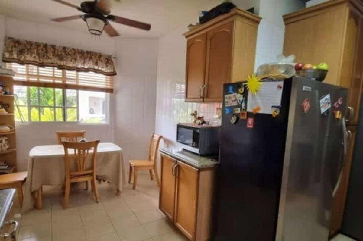 Front entry of house with columns, tiled porch, garden and bench at Palmeras del Este Panama