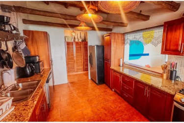 Rustic kitchen with wood beams, granite counters, pendant lights in beachfront house Nueva Gorgona Panama