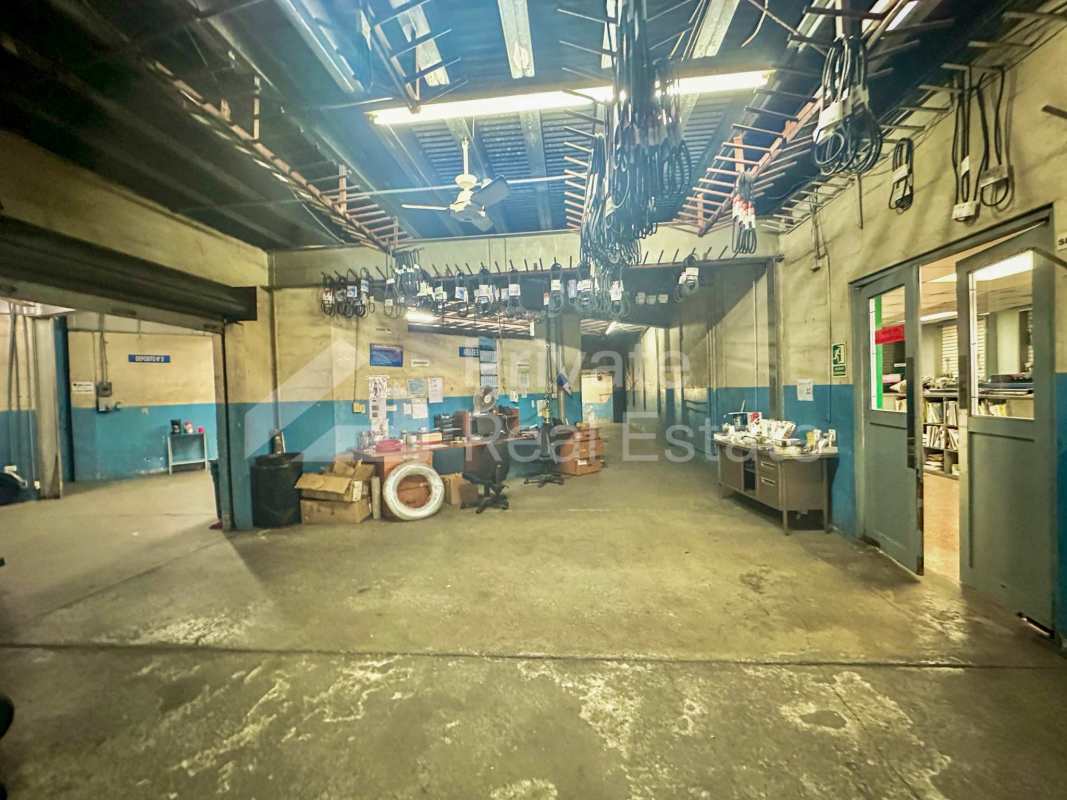 Workshop area with exposed ceiling, fluorescent lighting, work desks and concrete floor in Vista Hermosa Panama commercial building