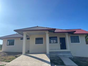 Cream single-story home with front porch and driveway in Bellas de Atalaya Santiago