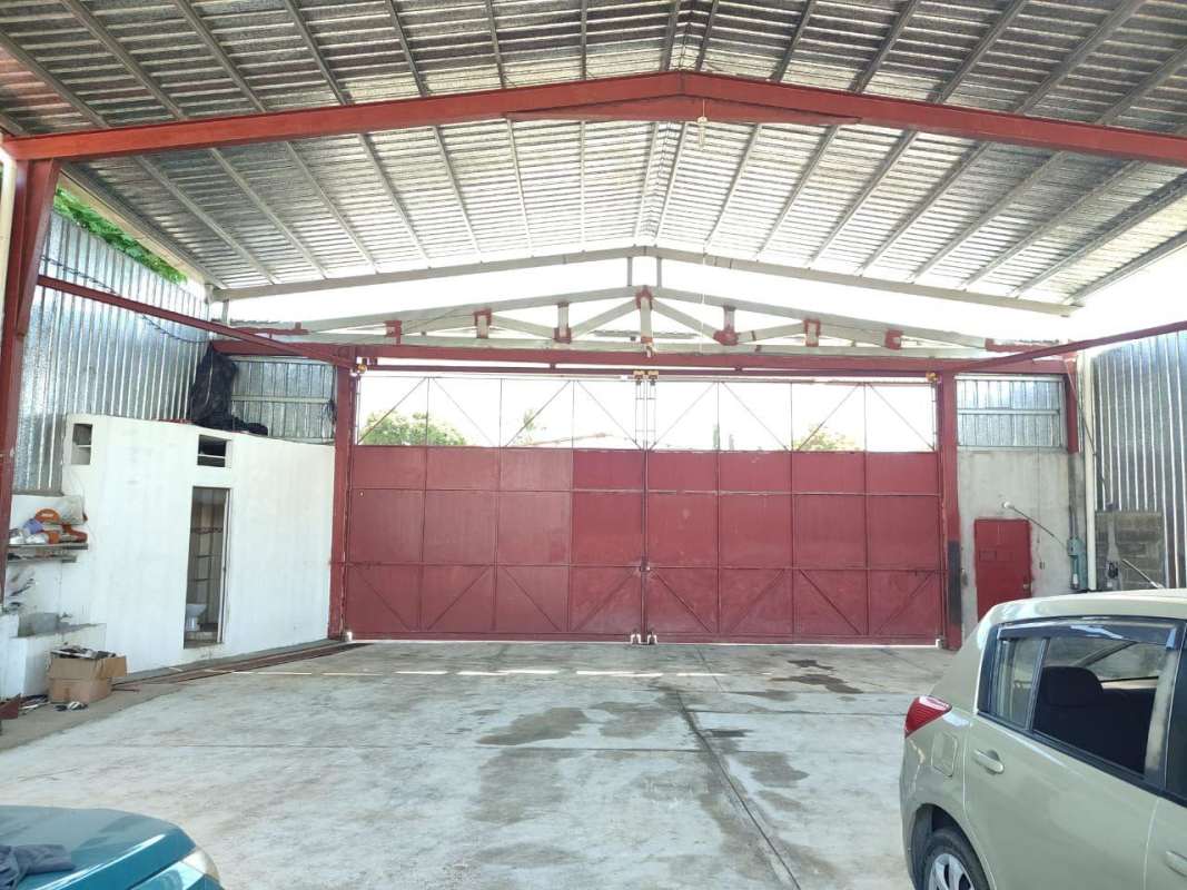 Inside warehouse with large metal red doors, concrete floor, corrugated metal walls in Rancho Café Panama City