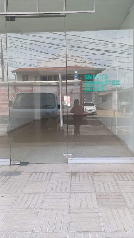 Glass storefront entrance with reflection of parked van Vista Hermosa Panama