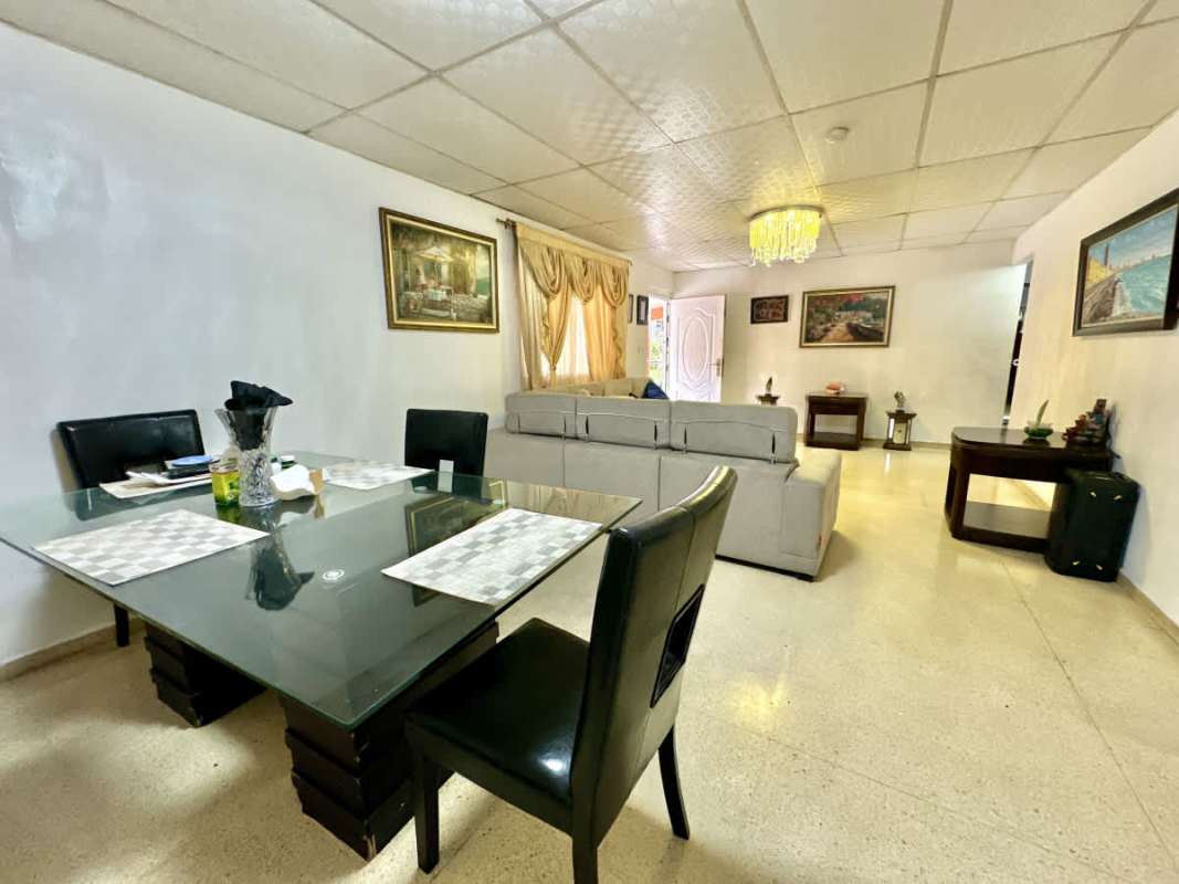 Bright living and dining room with glass table, sectional sofa and chandelier in Campo Verde Las Cumbres