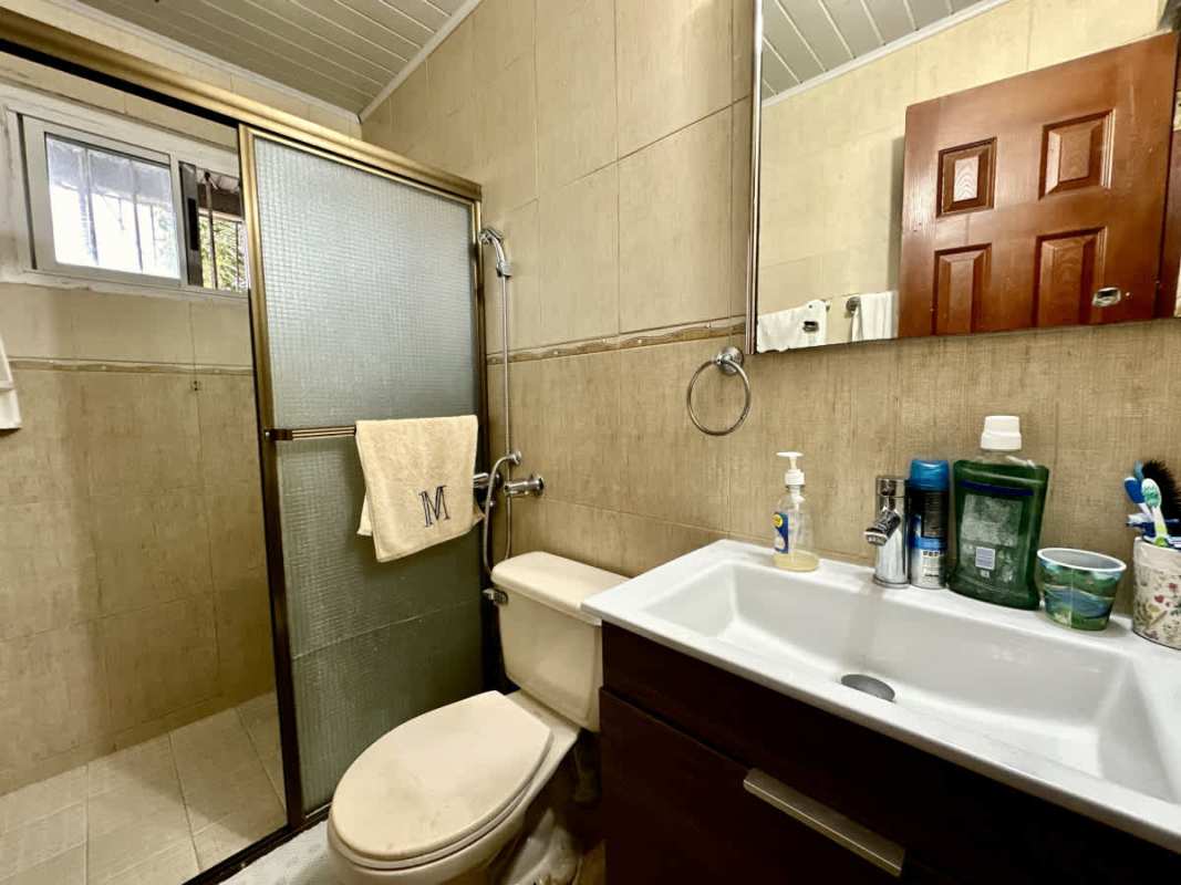 Bathroom with glass shower, tiled walls, vanity mirror in residential house Carroll Verde Las Cumbres Panama