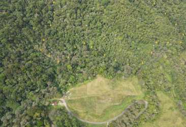 Aerial showing dirt road and cleared area surrounded by mountain forest in Panama