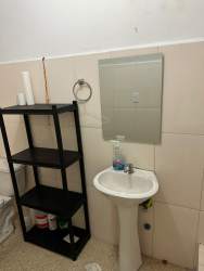 White and beige bathroom with sink, shelving, mirror in Costa Verde commercial unit