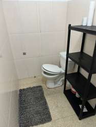White bathroom with toilet and shelving unit in commercial property Panama Oeste