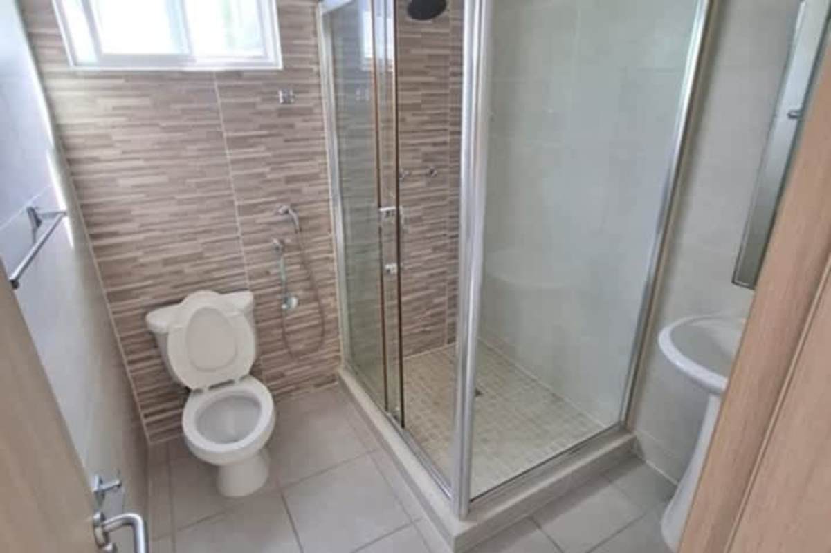 Updated bathroom with beige tiles glass shower enclosure white fixtures in Panama