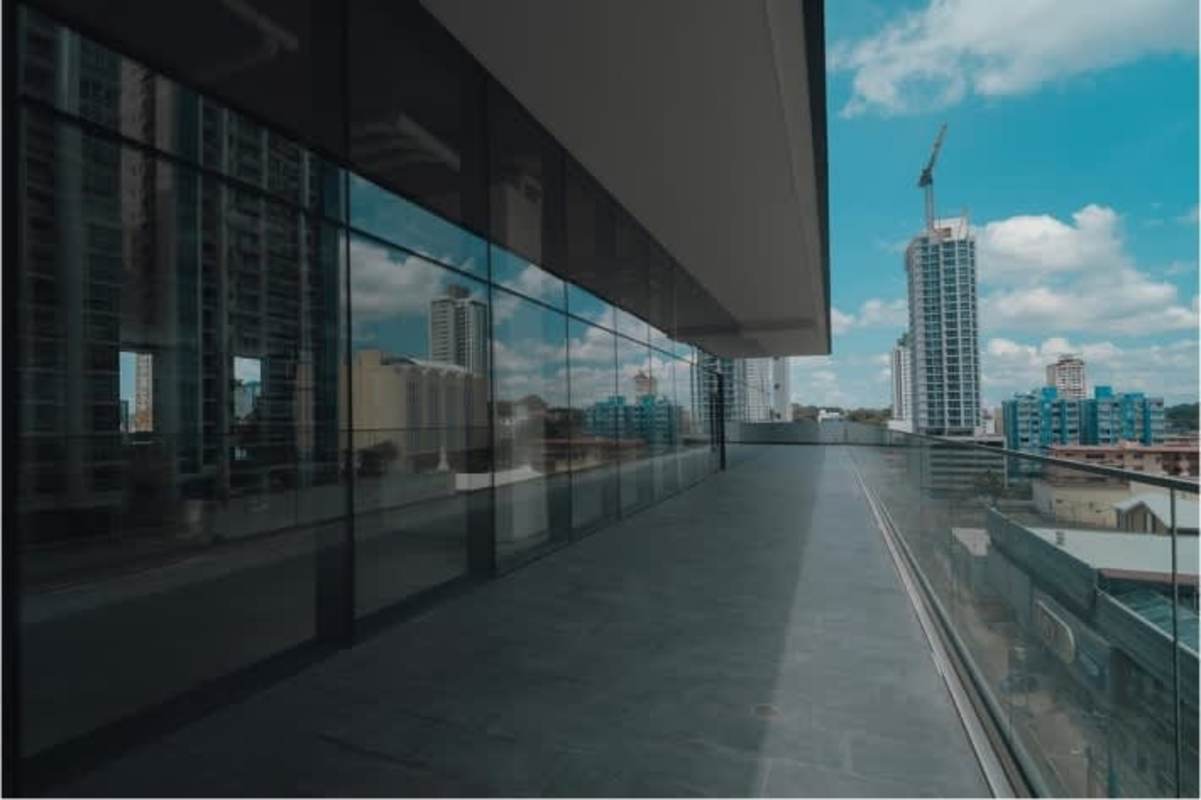Modern glass-fronted commercial building with balcony terrace and skyline views in Bella Vista Panama