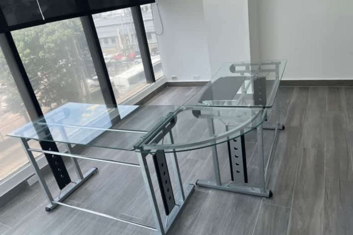 Minimalist design private office with glass L-shaped desk and city skyline view in BICSA Tower Panama City