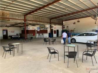 Fenced commercial warehouse with flat roof and large entry gate facing main road