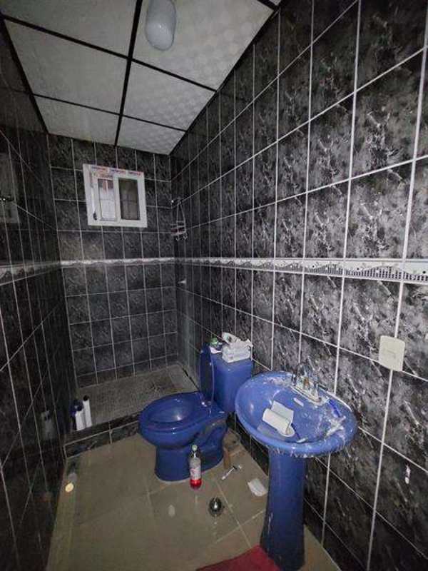 Bathroom featuring dark tile walls, pedestal sink and blue toilet in Las Cumbres Panama house