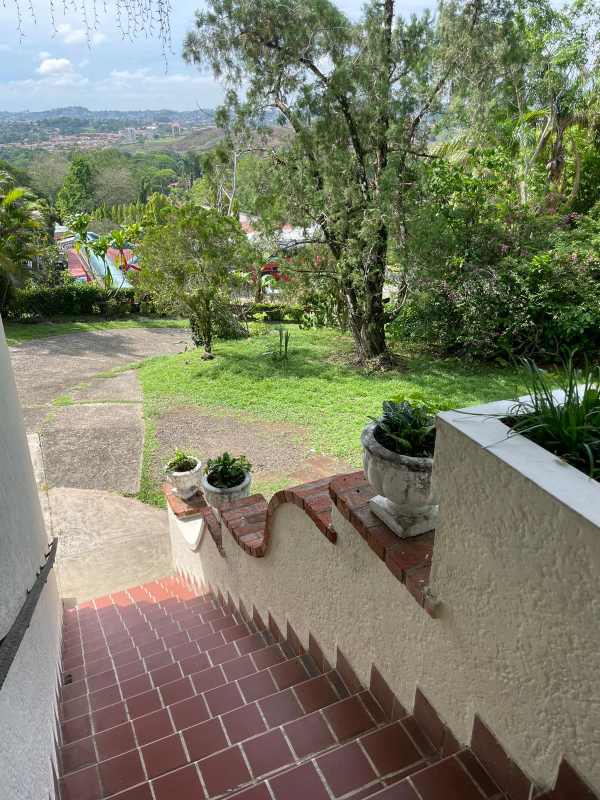 Mediterranean balcony with terracotta tiles, white iron chairs, view of hills in Las Cumbres Panama
