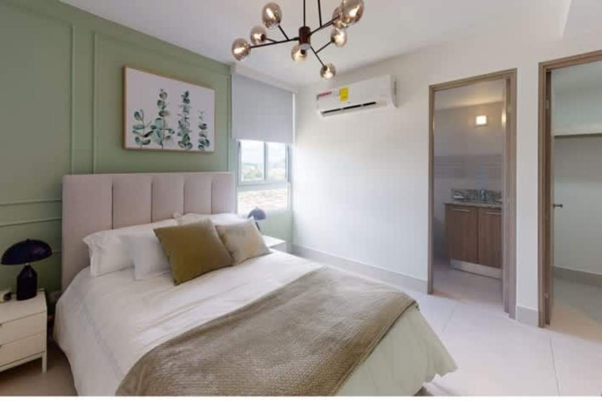 Modern bedroom with large window, green accent wall, upholstered bed at PH Greenwood San Miguelito
