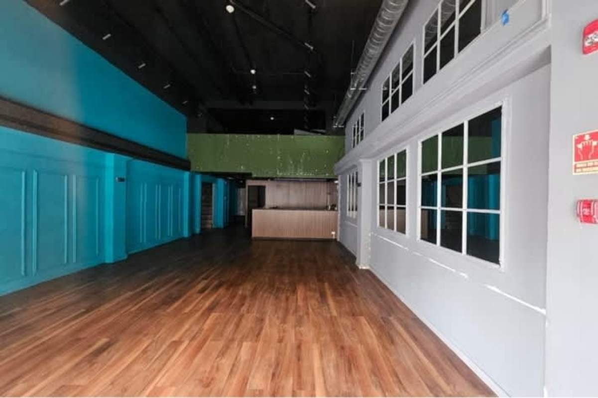 Spacious retail or office interior with wooden floors, teal walls, industrial ceiling Casco Viejo Panama