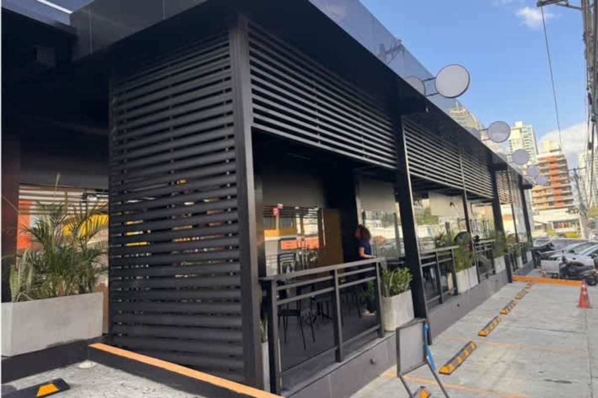 Black slatted modern commercial building facade with sidewalk and glass windows in San Francisco Business Plaza Panama City