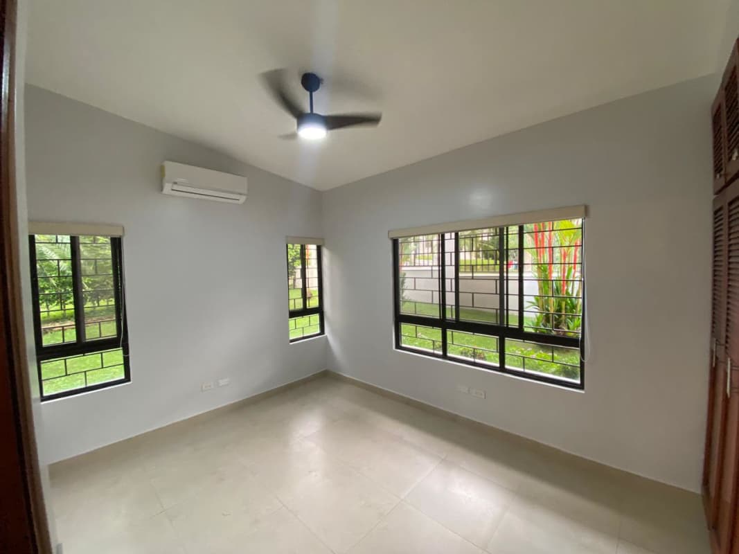 Spacious bedroom with wardrobe, AC and large window overlooking greenery in gated home Clayton Panama