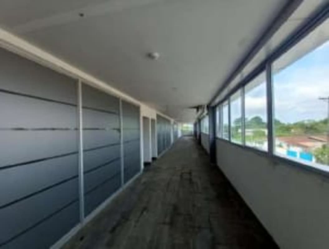 Long enclosed corridor with large windows and gray panel walls Villas de Santa Barbara Tocumen