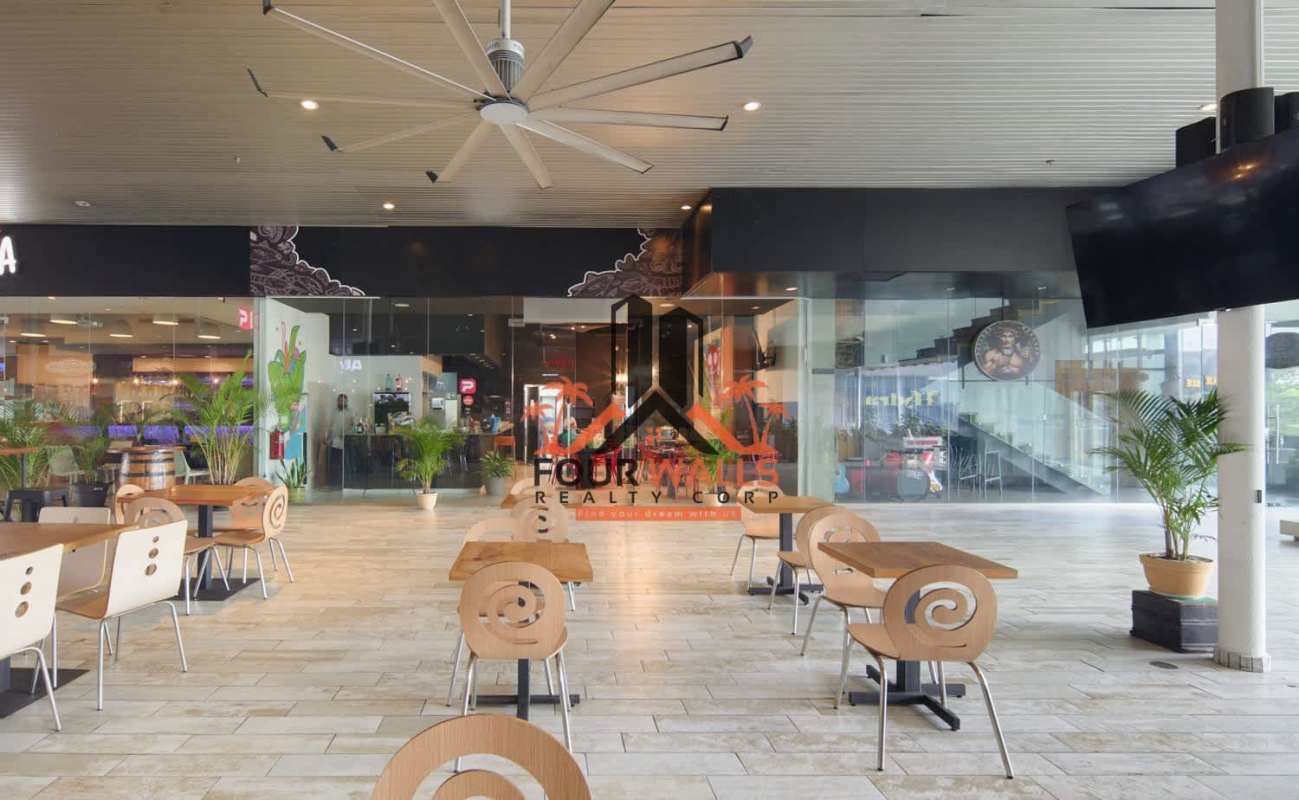 Covered outdoor terrace with wood furniture and glass storefront at Balboa Boutiques in Panama City