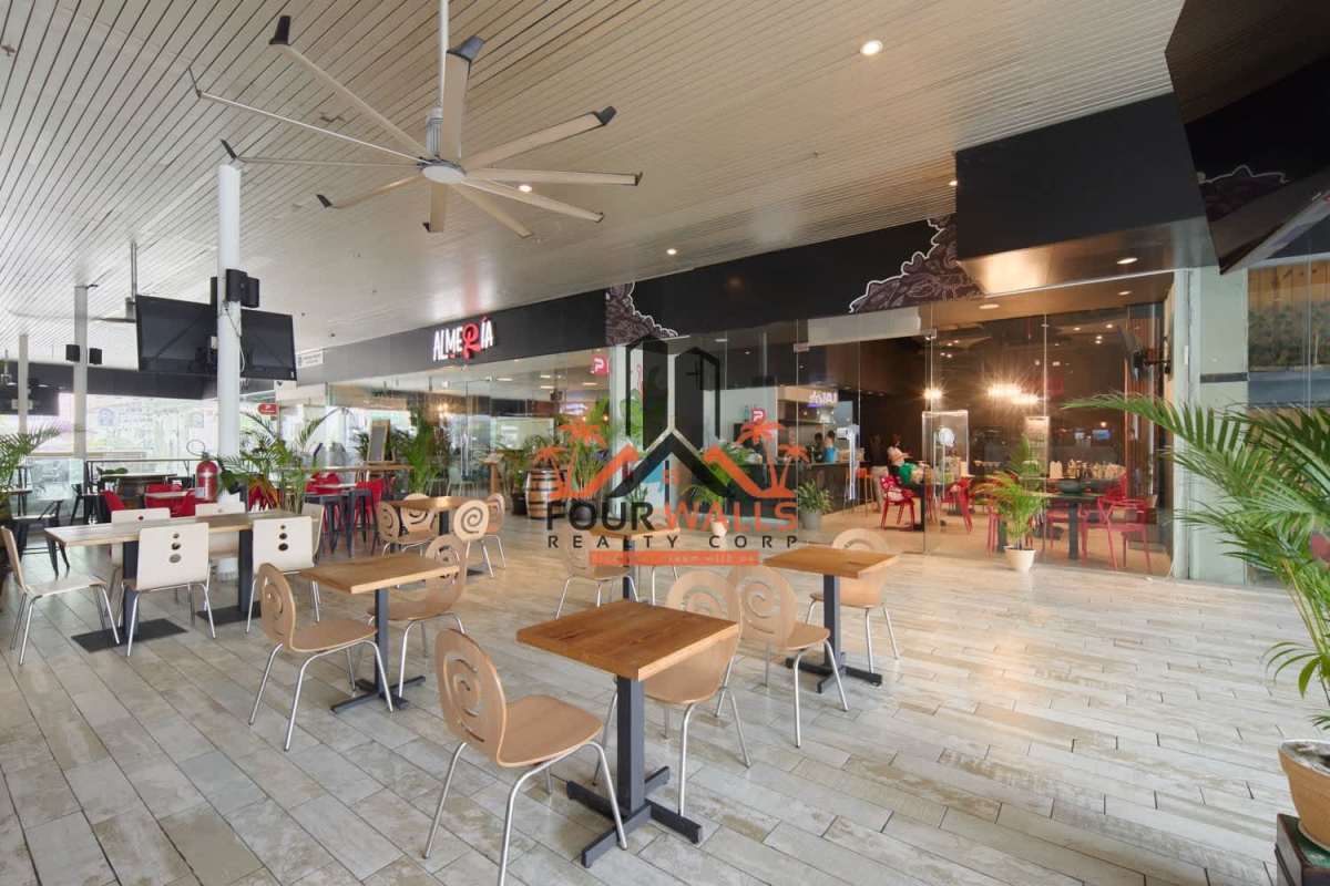 Modern dining area in commercial space with glass walls and wood furniture at Balboa Boutiques Panama City