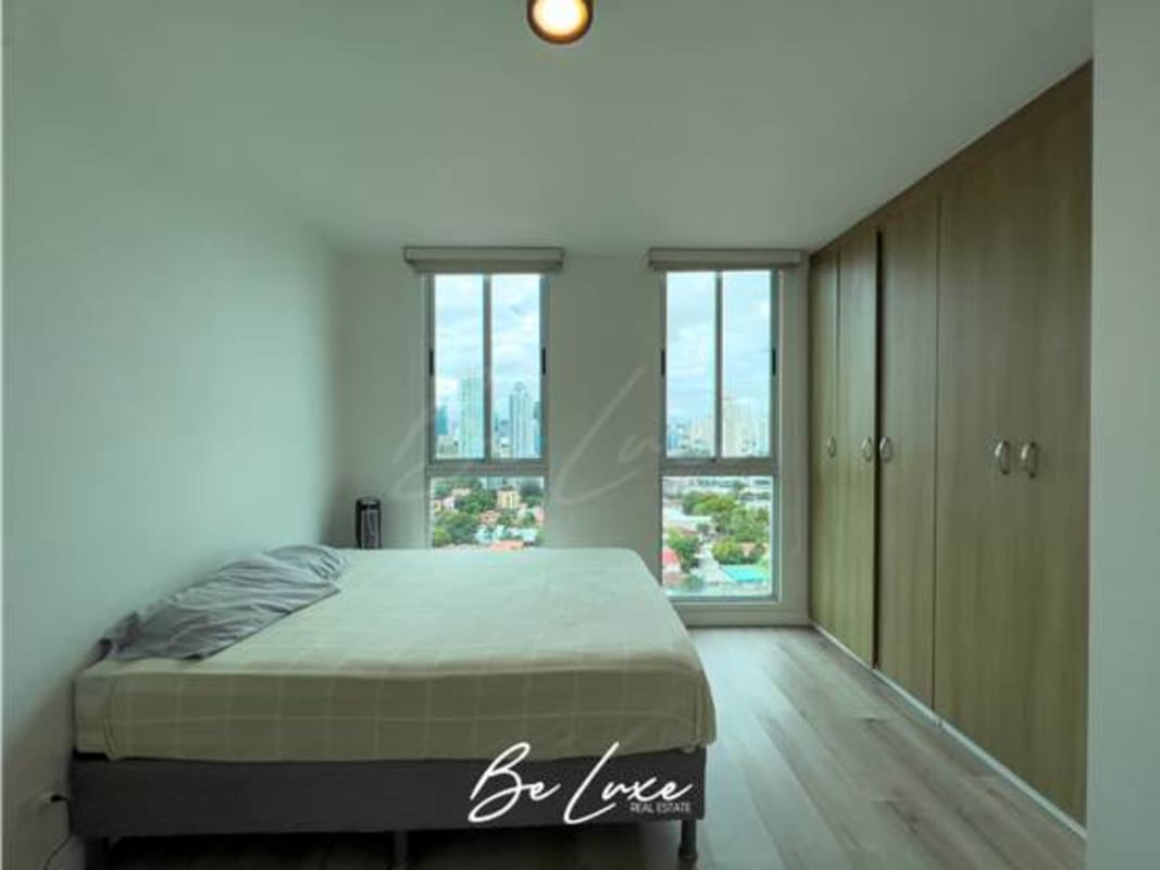 Furnished master bedroom with panoramic windows overlooking Panama City skyline at PH Harmony Tower San Francisco Panama